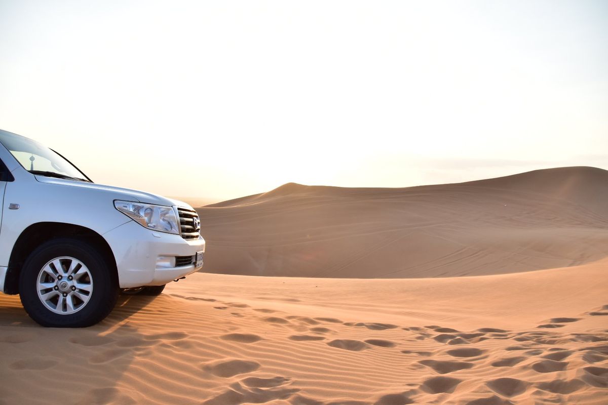 Ein Geländewagen vor roten Sanddünen in der Wüste bei Dubai