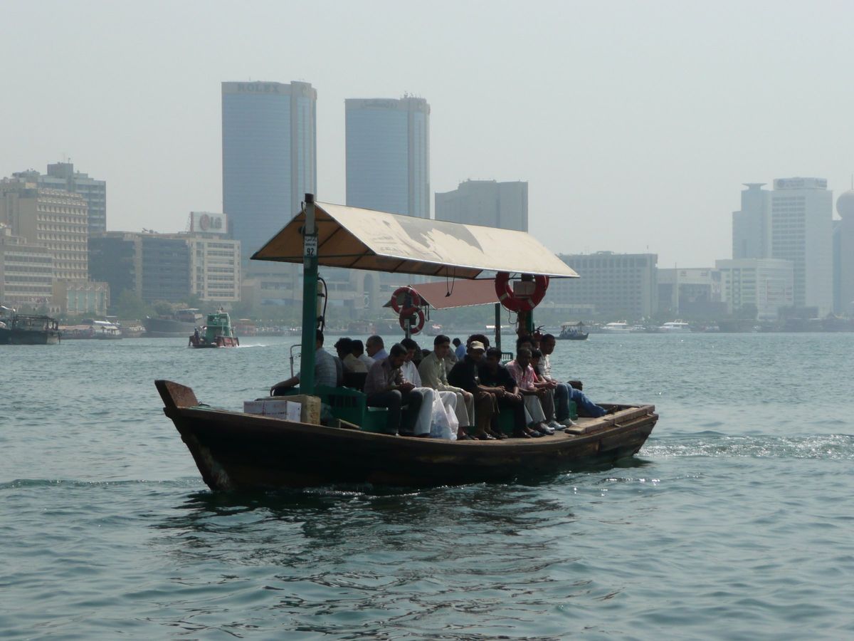 Eine voll besetzte Abra auf dem Dubai Creek vor der Skyline von Deira