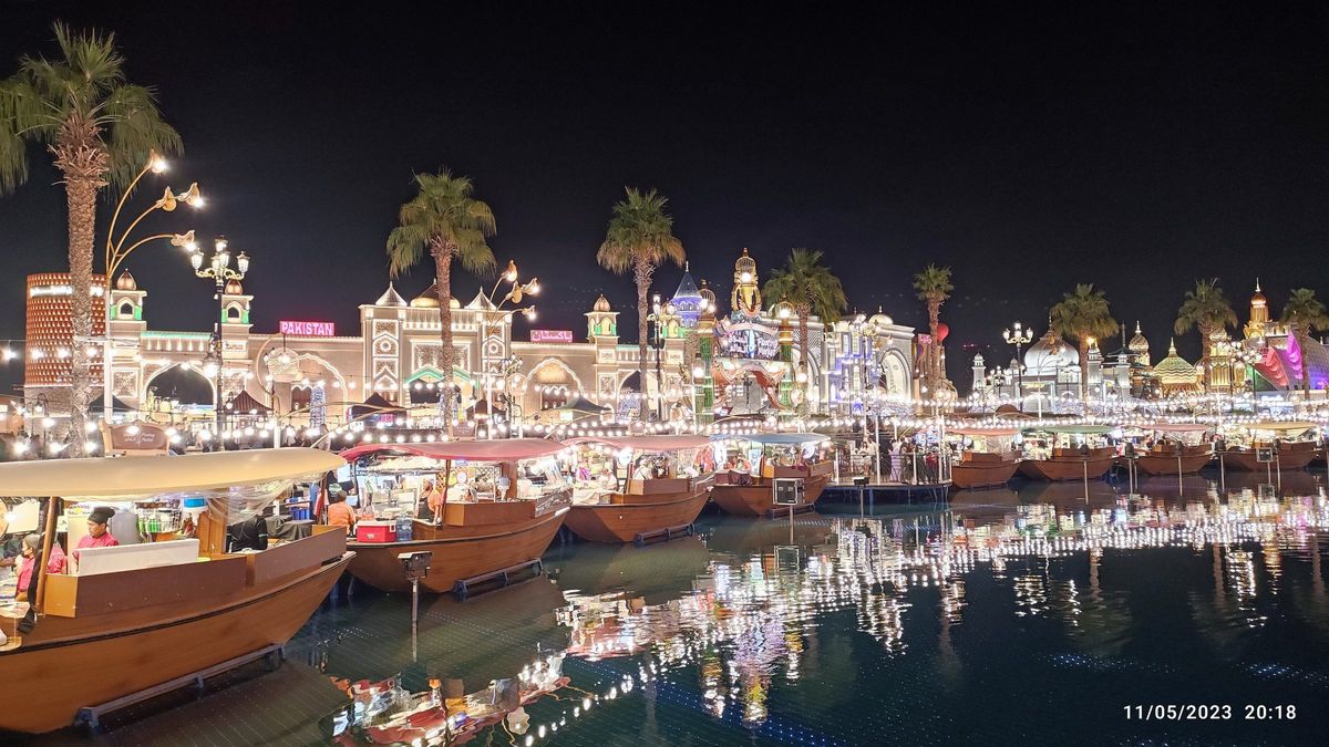 Beleuchtete Pavillons und Boote am Wasser im Global Village Dubai bei Nacht